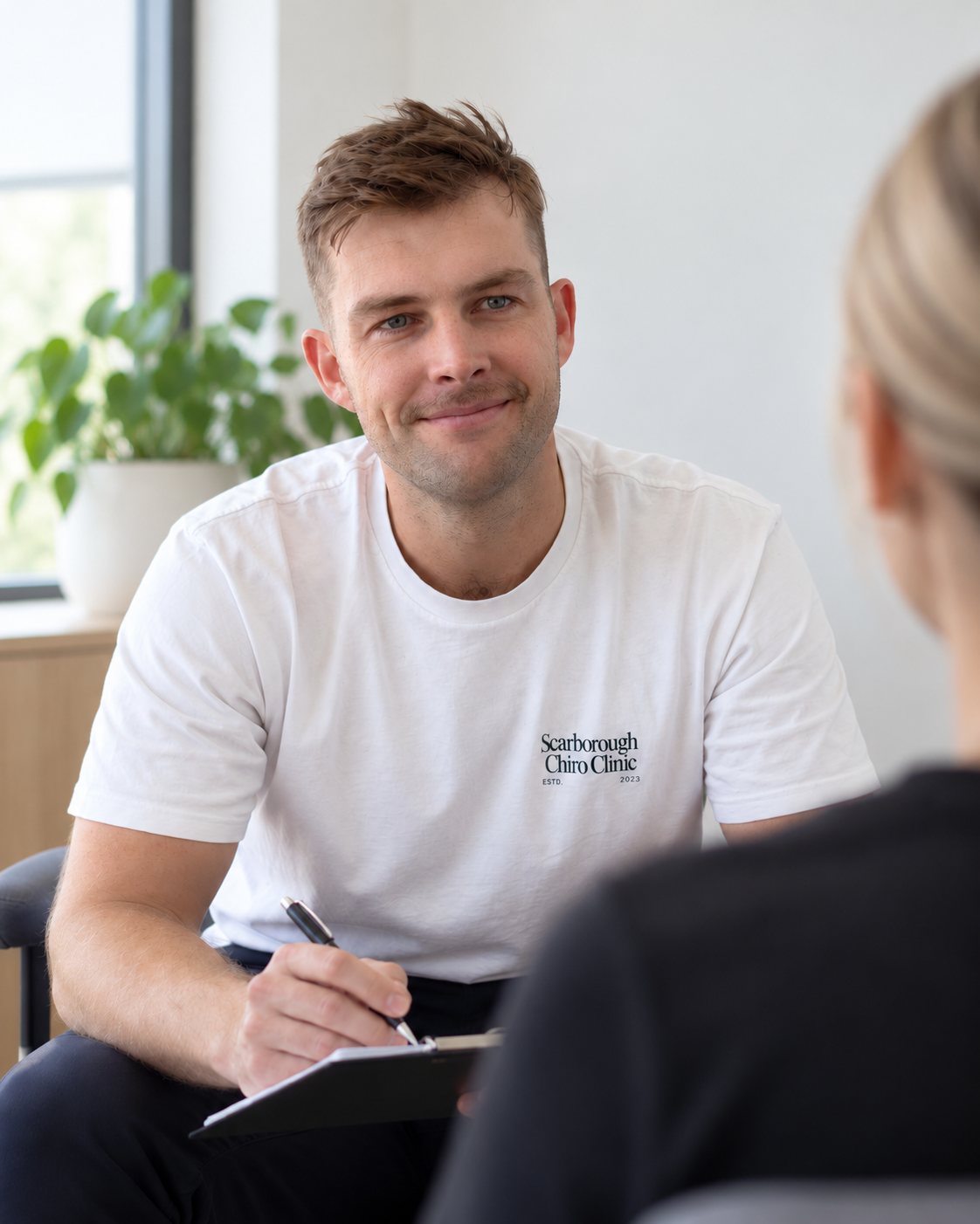 Tim listening to a patient and taking notes during a consultation