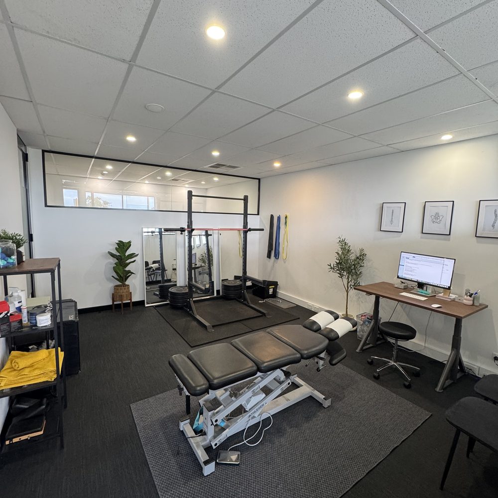 Rehab room with squat rack, mirror, treatment table and desk