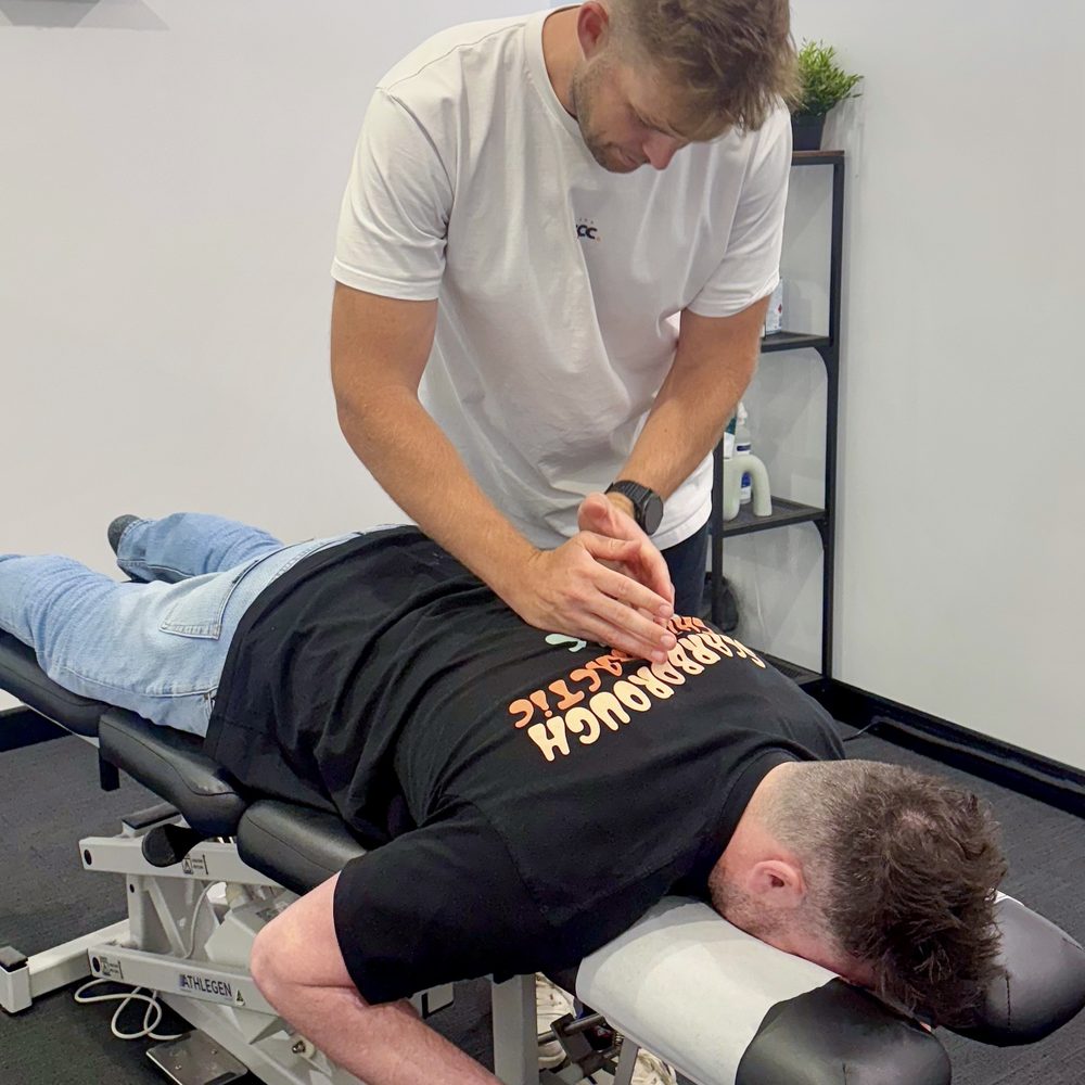 Tim White treating a patient lying on the chiropractic table